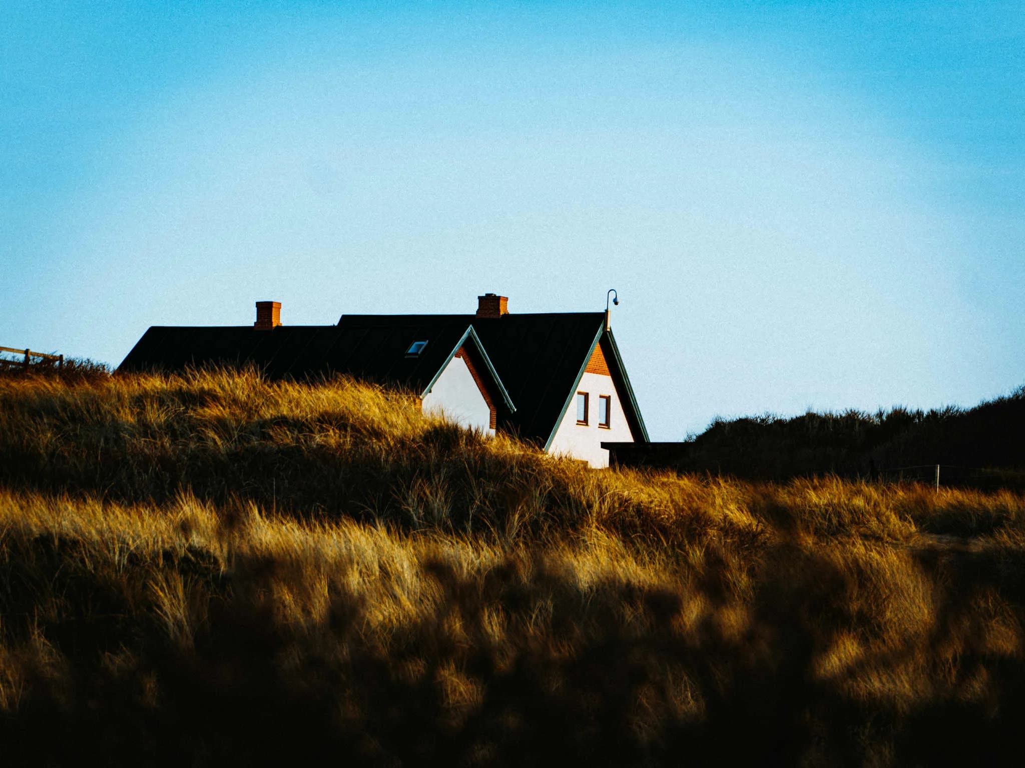 Dansk sommerhus i klitterne ved Vesterhavet i gyldne timer.